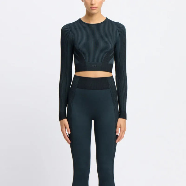 A woman wearing a long-sleeve seamless Reebok top in black and a raised Reebok logo at the front.