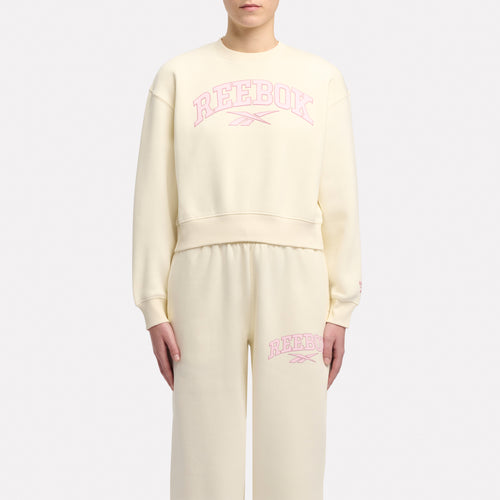 Person wearing a light yellow sweatshirt and pants with 'Reebok' branding on a white background