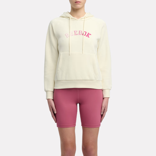 Person wearing a cream hoodie with pink text and pink shorts on a white background