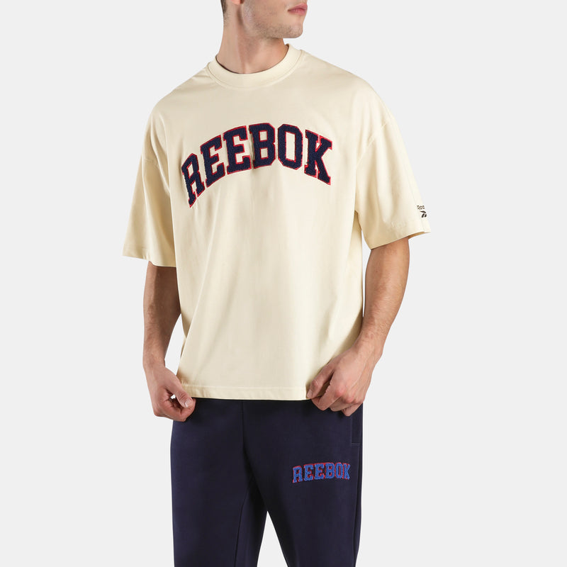 Person wearing a cream Freshman Men's Reebok t-shirt and navy pants on a white background